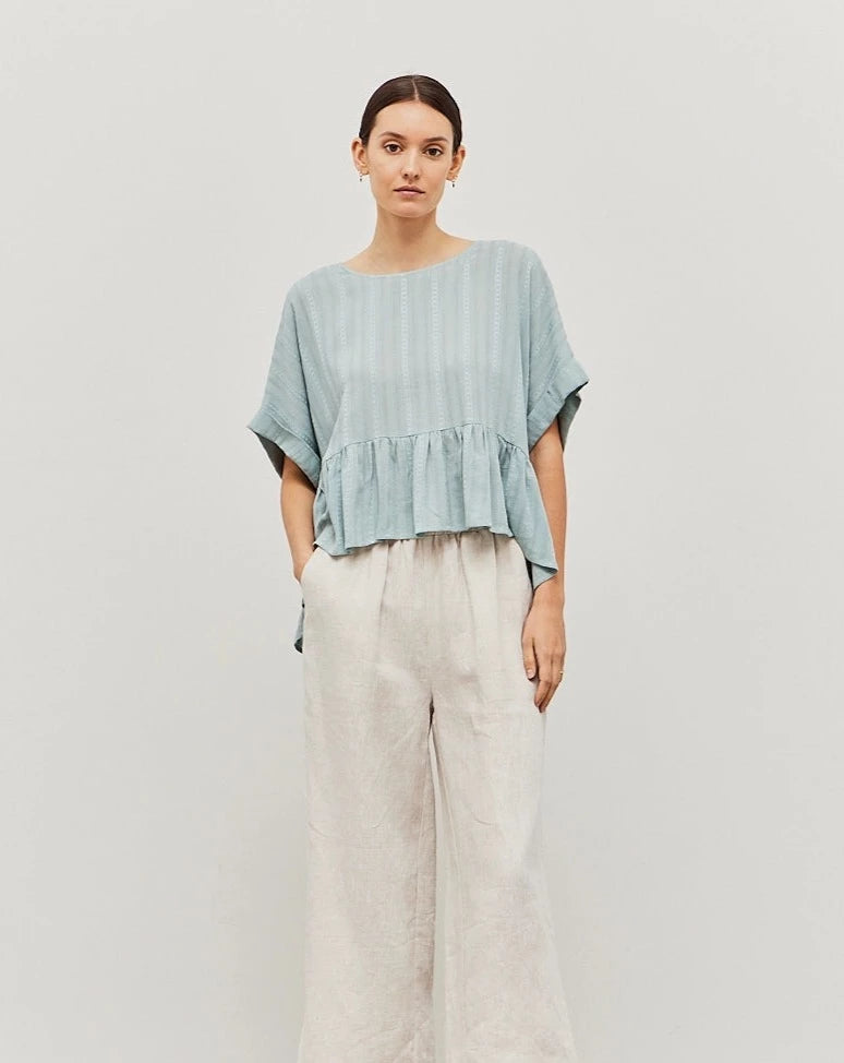 The Woven Ruffle Top is a look that will look fabulous with your entire wardrobe. It features a sweet peplum detail and a breezy material, a staple for that summer to fall transition.
